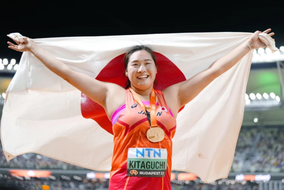 女子やり投げで金メダルを獲得し、日の丸を掲げ笑顔の北口榛花選手 【共同通信】