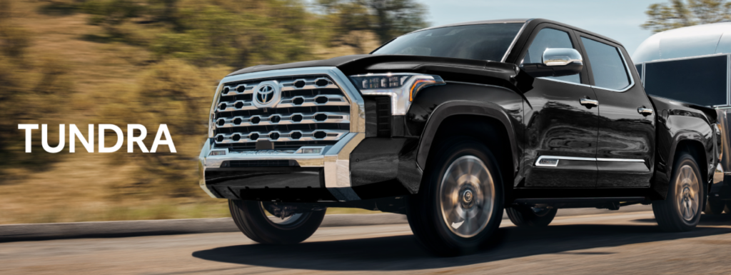 キャンピングカーをけん引している黒いTUNDRAの画像。